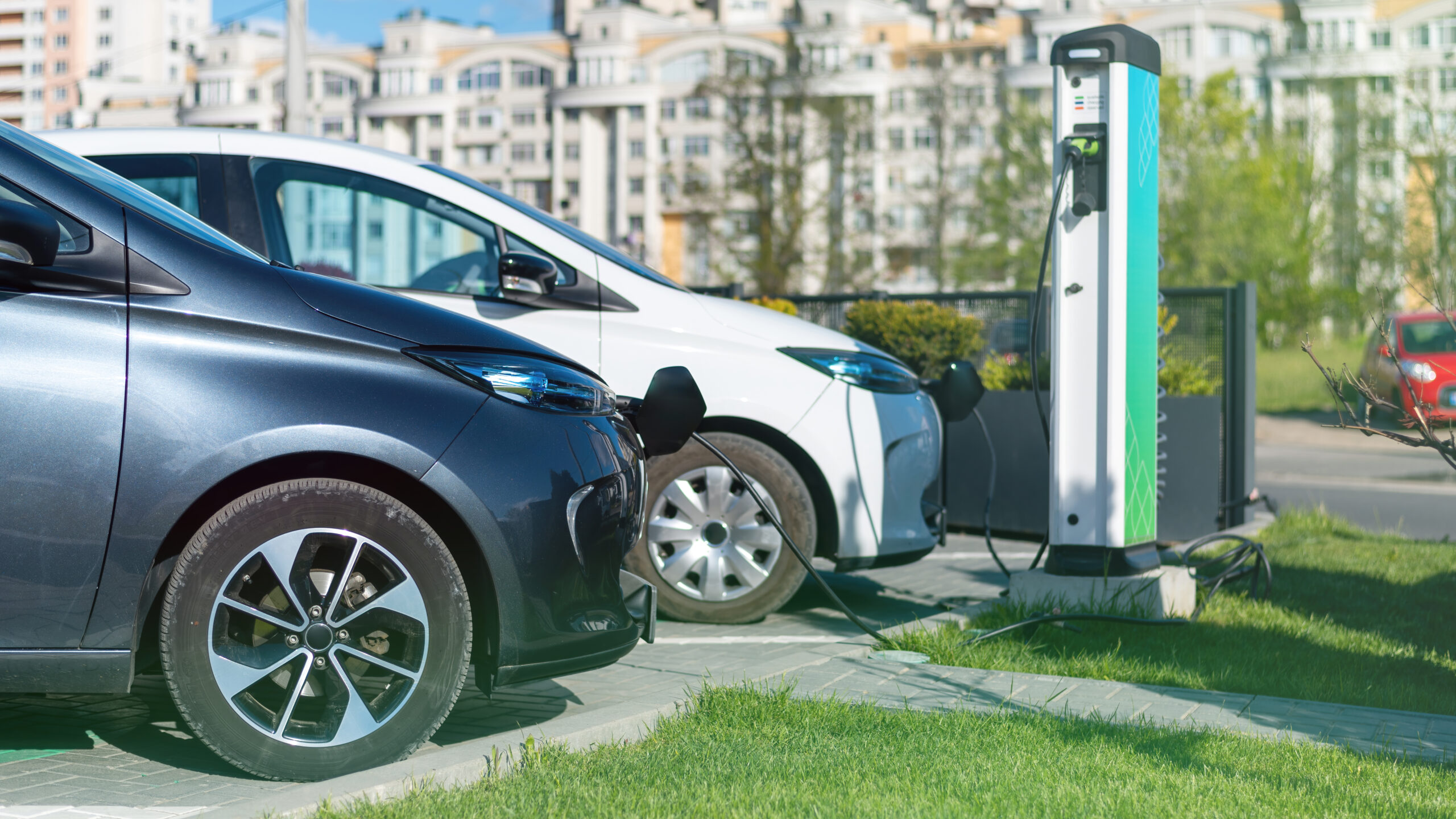 Zwei Elektroautos an Ladepunkten auf einem Parkplatz – Symbolbild