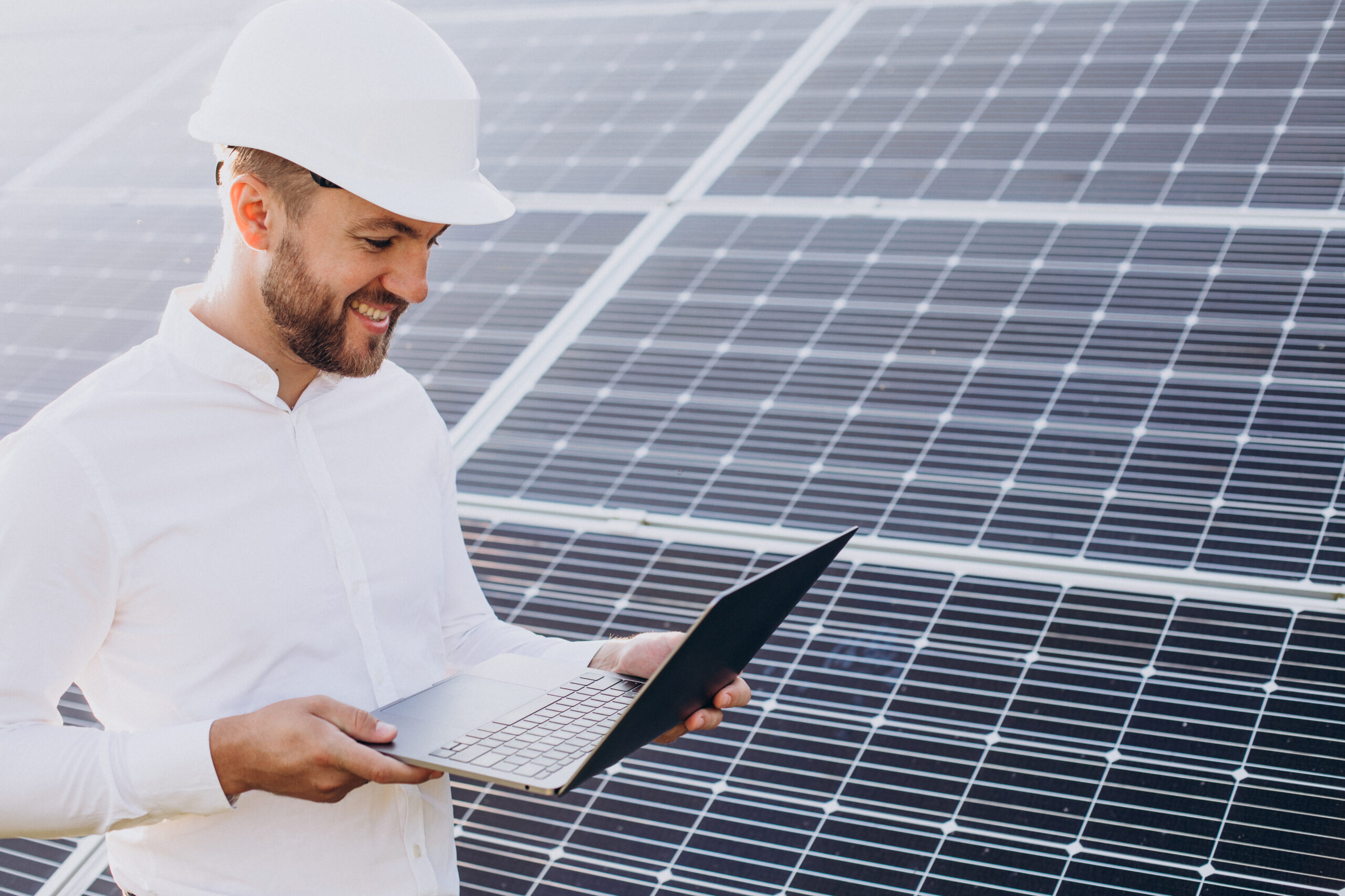 Person mit Notebook vor Photovoltaikmodulen – Symbolbild