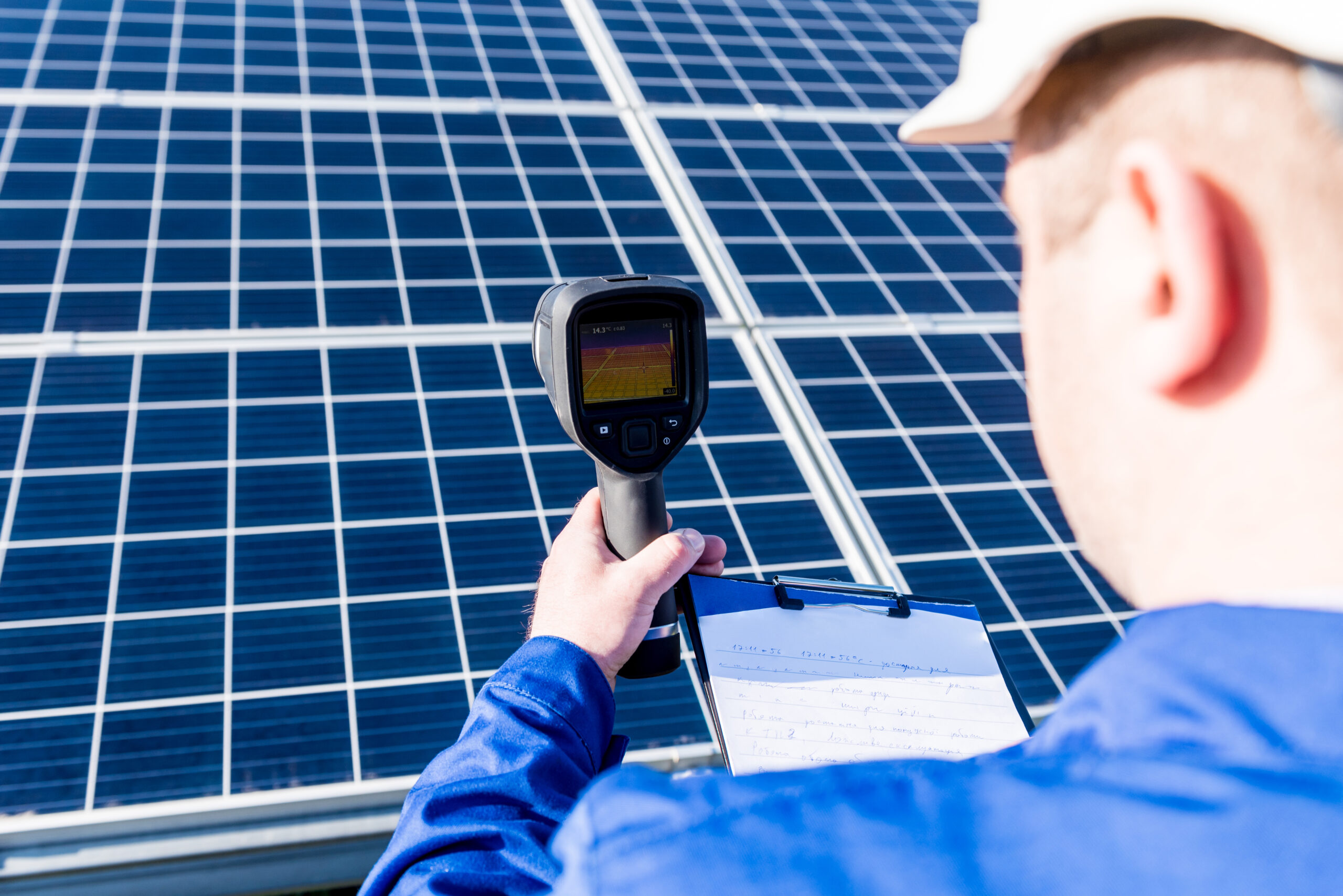 Person mit Wärmebildkamera vor Photovoltaikmodulen – Symbolbild