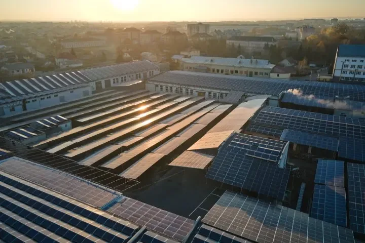 Luftaufnahme eines Industriegebäudes mit blauen Solarmodulen auf mehreren Dachflächen
